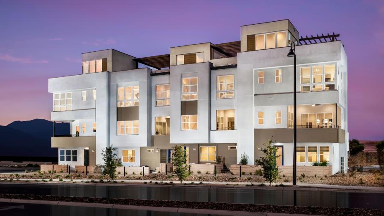 Exterior street view of multi-level attached townhomes with varied facade materials