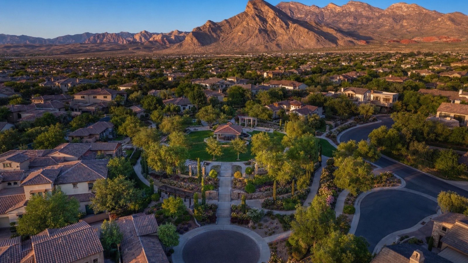 Aerial of The Gardens village in Summerlin South with a central park, gazebo, tile-roof homes and the Spring Mountains behind