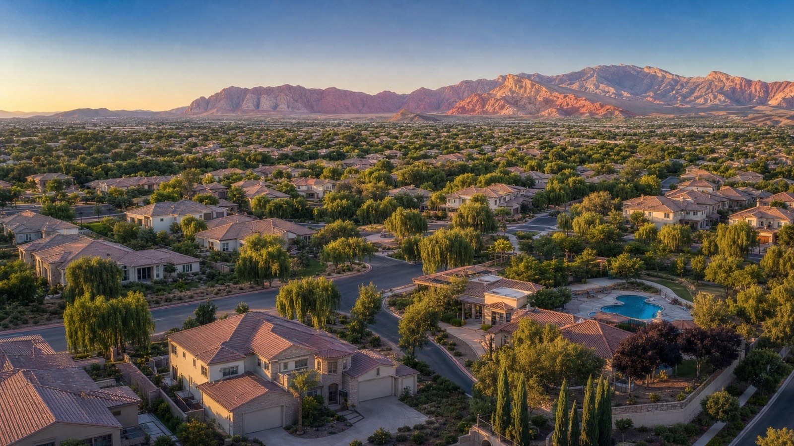 Aerial of The Willows village in Summerlin at sunset with a pool, curving streets and the Red Rock mountains
