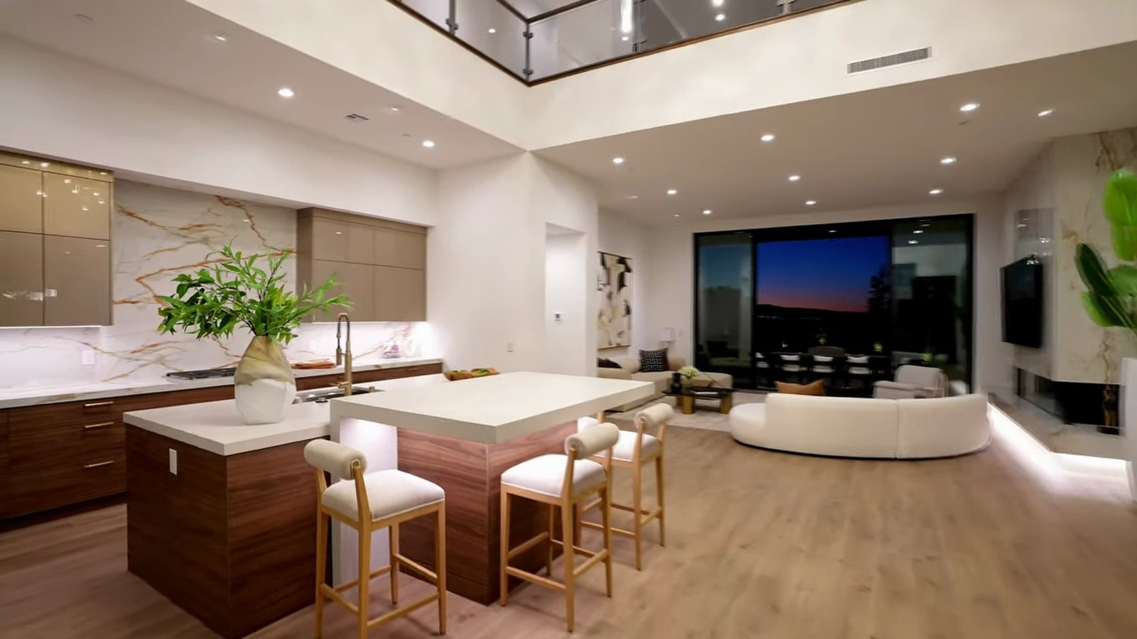 SkyVu kitchen at 521 Overlook Rim with a stone island, walnut cabinetry, veined backsplash and an open great room with valley views at dusk