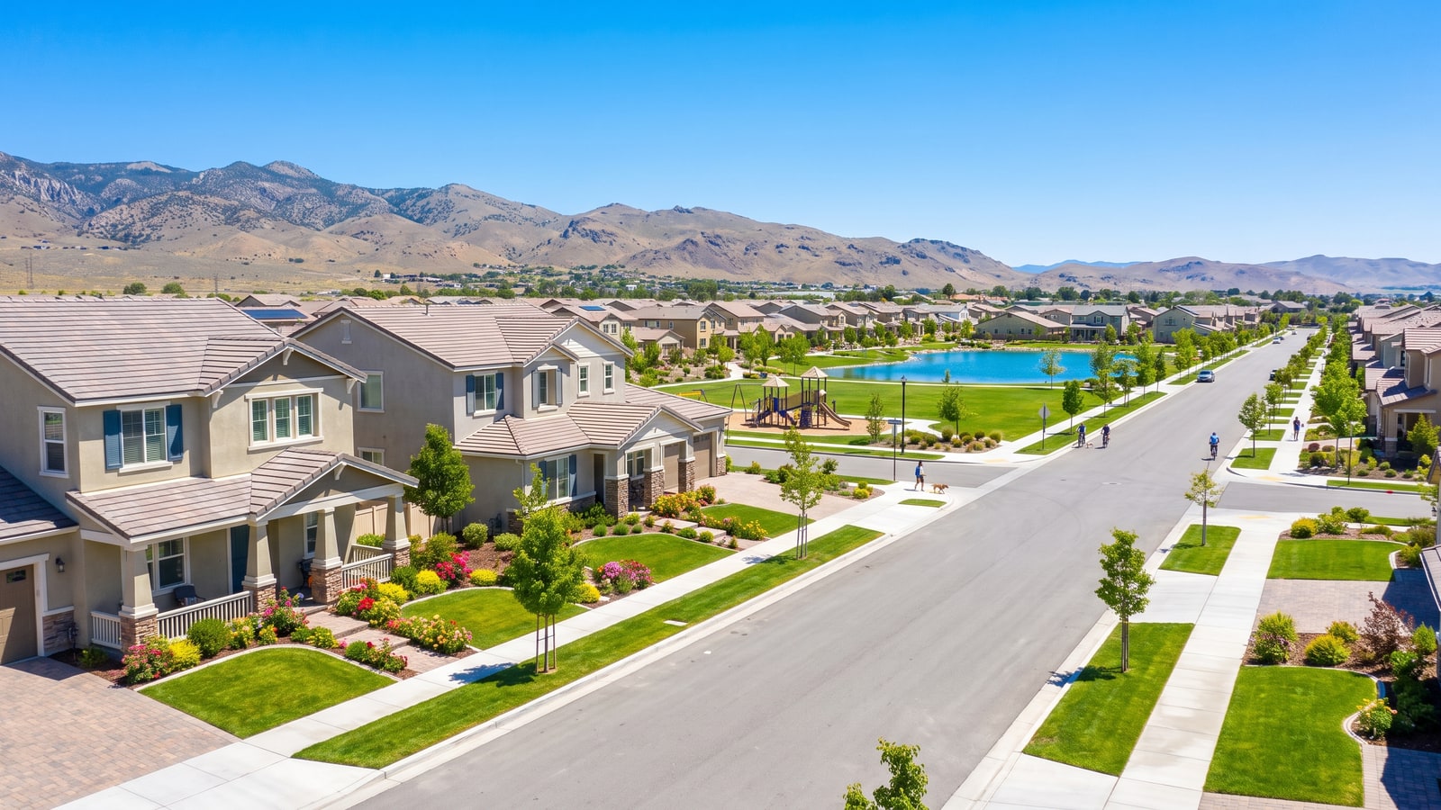 Family homes with green lawns, sidewalks, and a park along a Damonte Ranch streetscape in South Reno with Sierra foothills behind