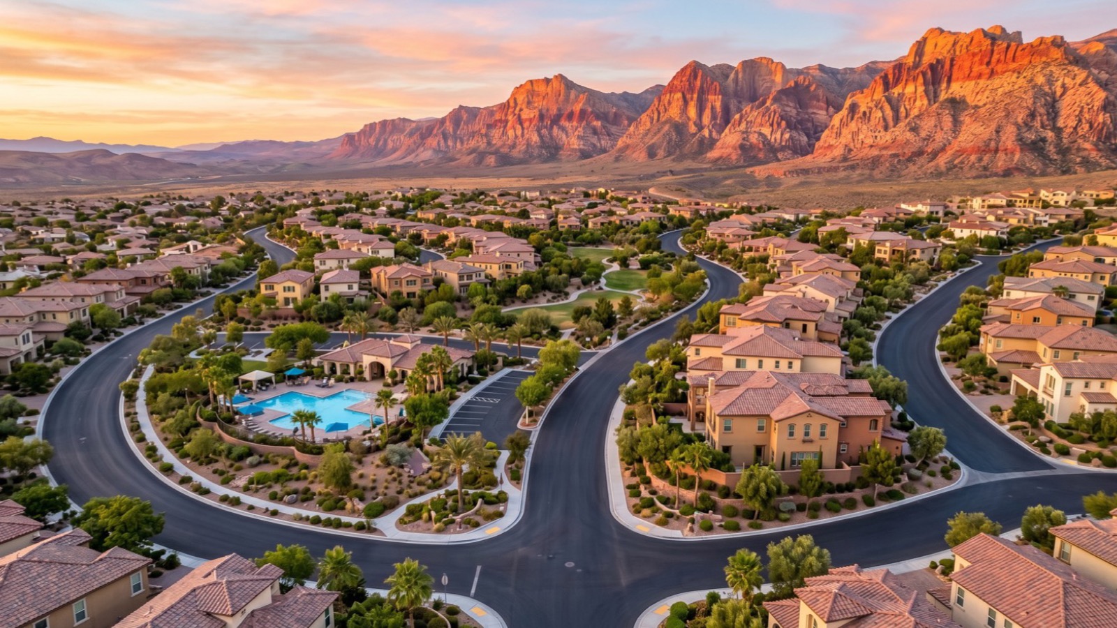 Aerial of a Summerlin neighborhood with a community pool and curving streets below the red sandstone of the Red Rock escarpment