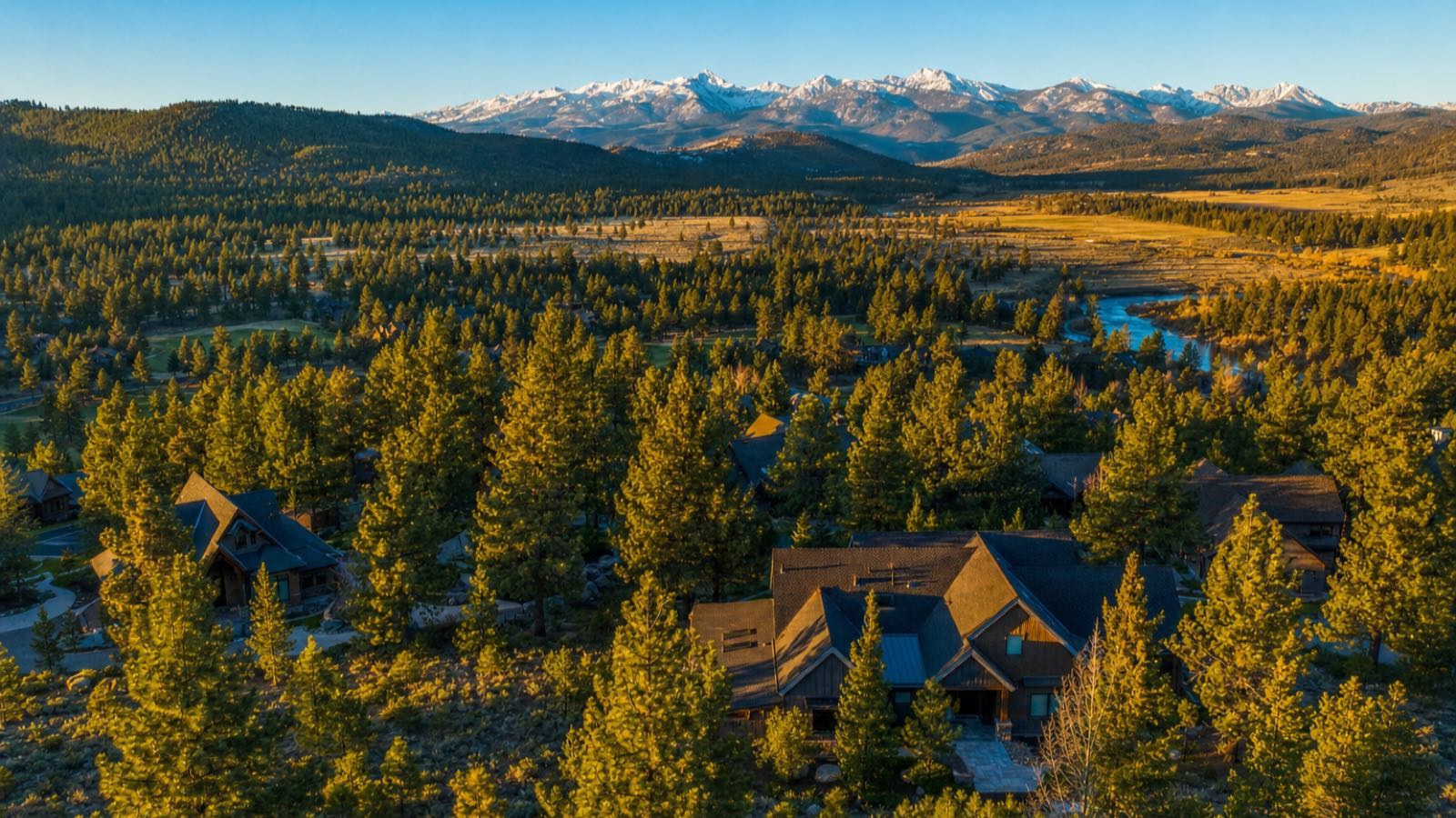Aerial view of pine-covered homesites in the Verdi area west of Reno Nevada with a river corridor and snow-capped Sierra peaks