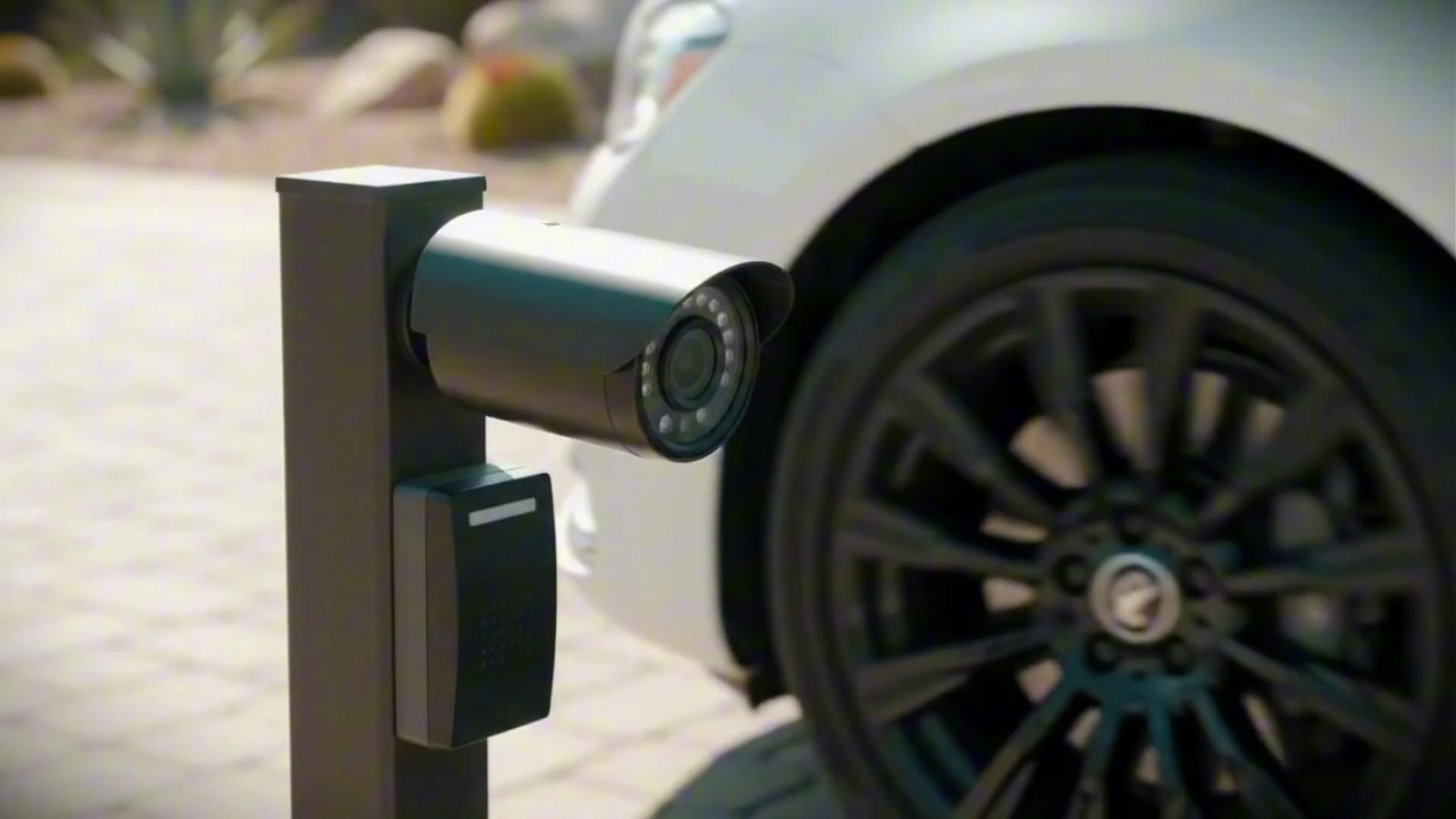 Illustration of a security camera on a post beside the wheel of a parked white car