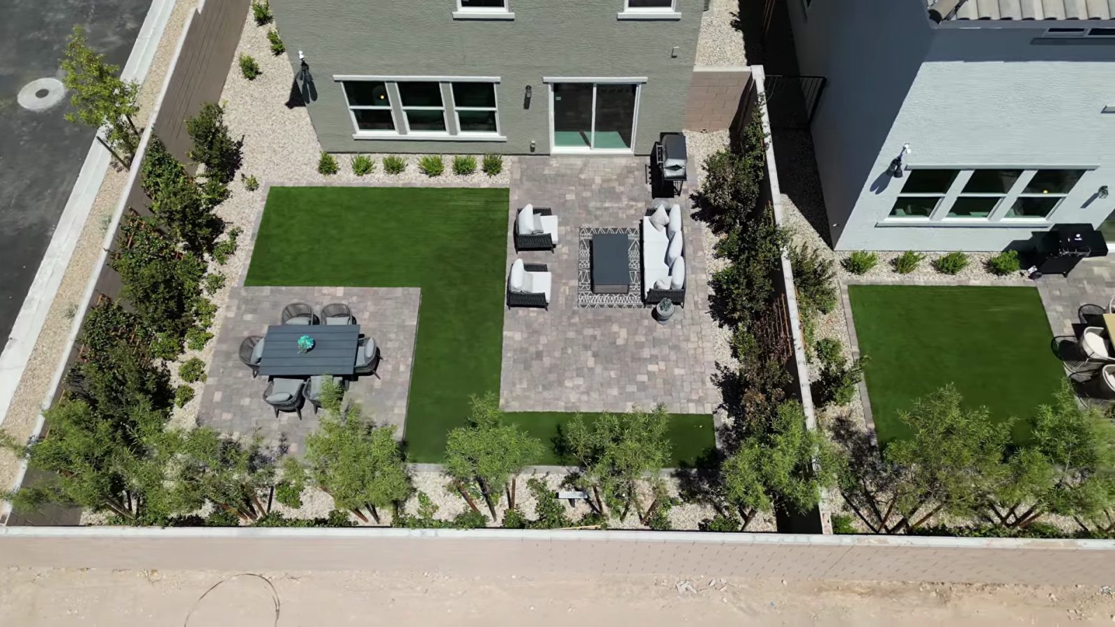 Aerial view of the finished model backyard at Landings at Aven with artificial turf, paver patios, outdoor furniture and desert planting