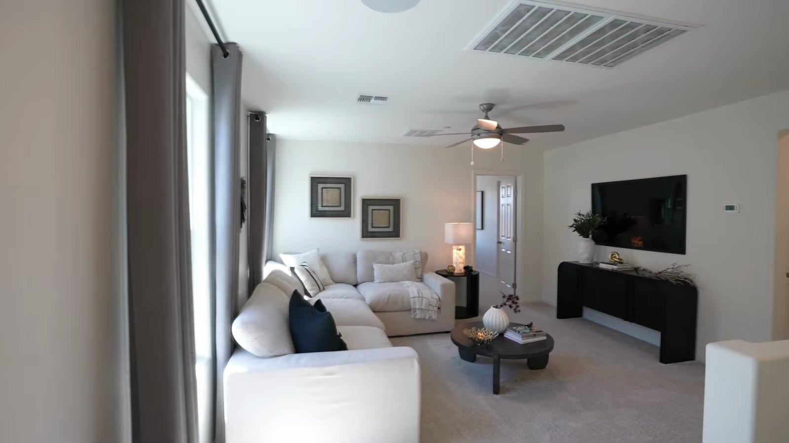 Upstairs loft in the KB Home Plan 2069 model at Landings at Aven furnished with a sectional, coffee table and wall-mounted television