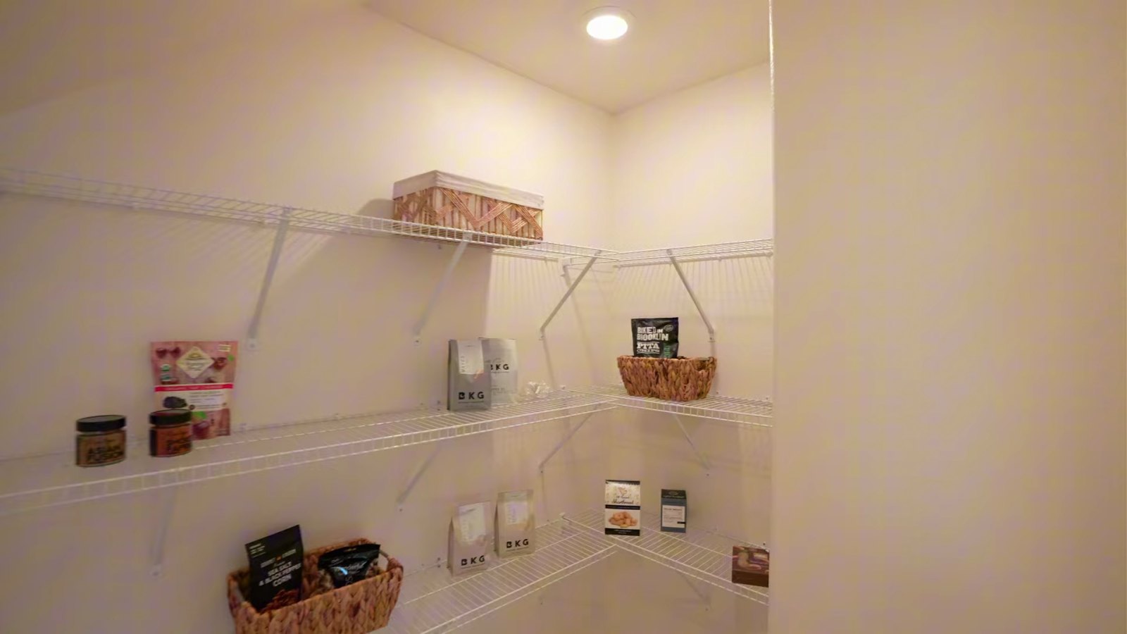 Walk-in pantry under the stairs in the KB Home Plan 2069 model with white wire shelving on two walls