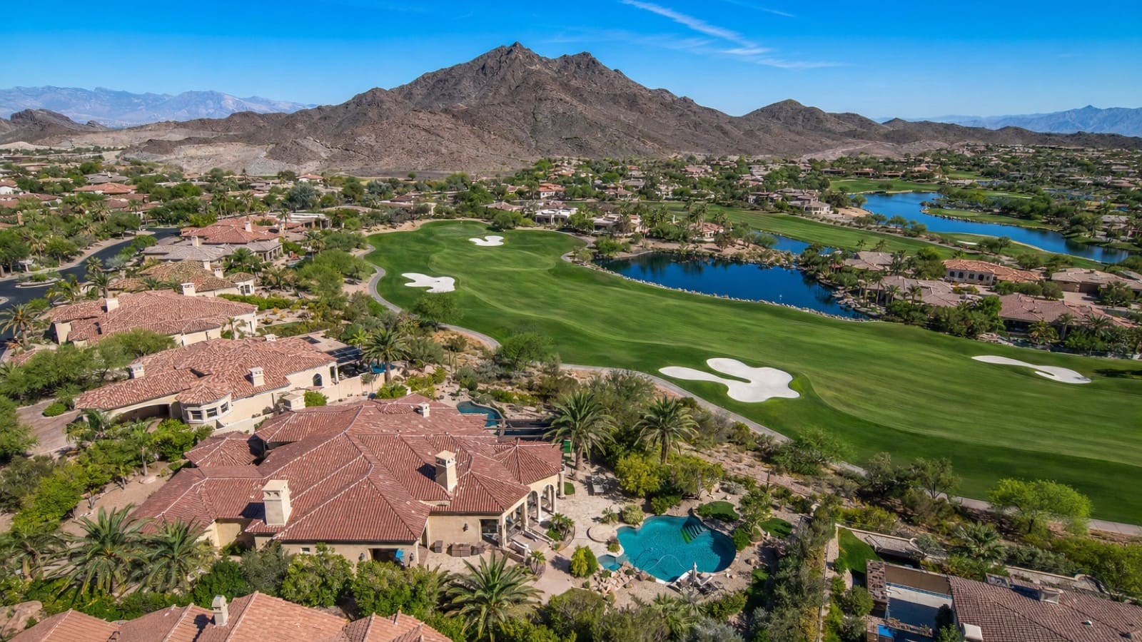 Illustration of tile-roof estate homes and a pool beside a golf fairway, with lakes and a desert mountain behind