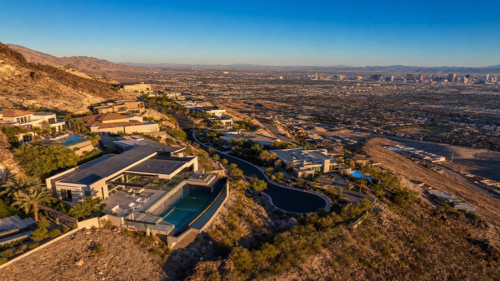 Aerial view of MacDonald Highlands in Henderson — hillside mansions above DragonRidge Country Club with the Las Vegas Strip in the distance