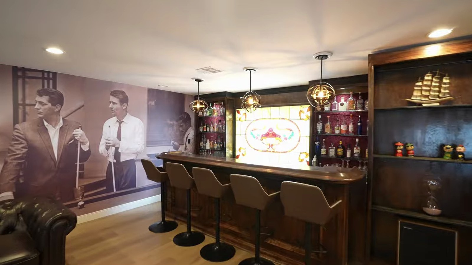 Original 530-square-foot bar room at 1400 Maria Elena Drive with a wooden bar, stained-glass panel, lit shelving and a vintage entertainer mural