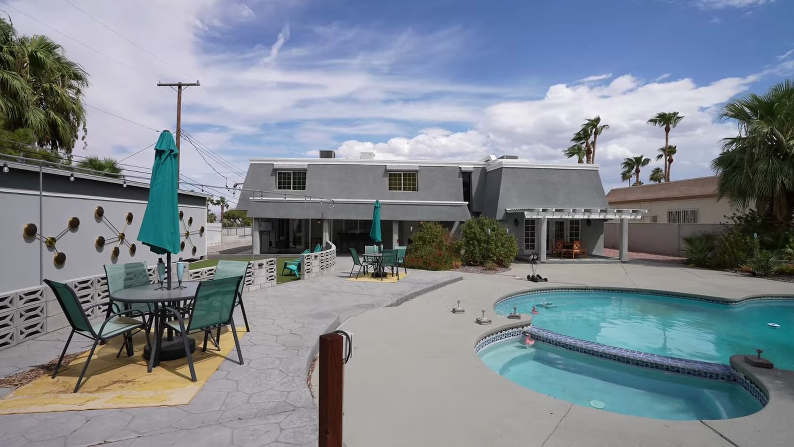 Backyard at 1400 Maria Elena Drive with a curved pool and spa, patio table, mature palms and the rear of the two-story 1970 house