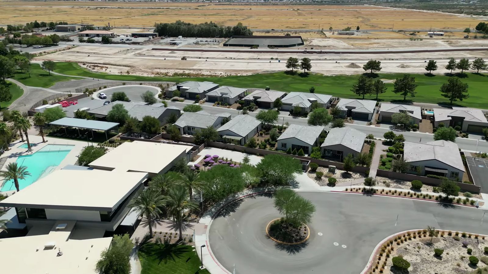 Aerial view of single-story homes, a clubhouse pool and a golf course at Ovation at Mountain Falls in Pahrump, with open valley land behind