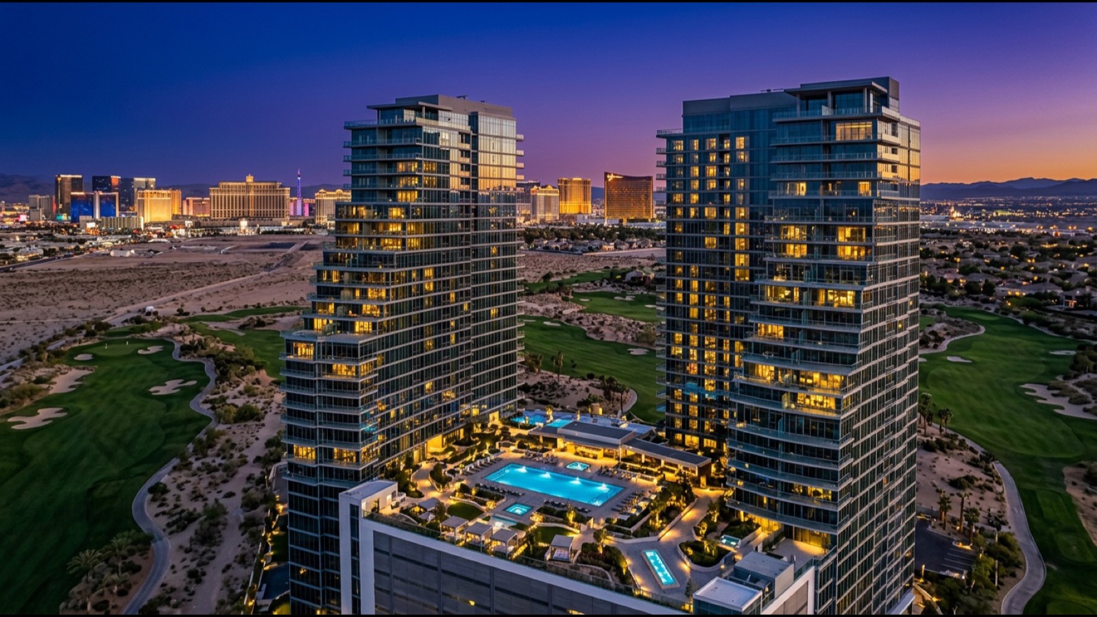 Twin residential condominium towers above a golf course at dusk with the Las Vegas Strip on the horizon