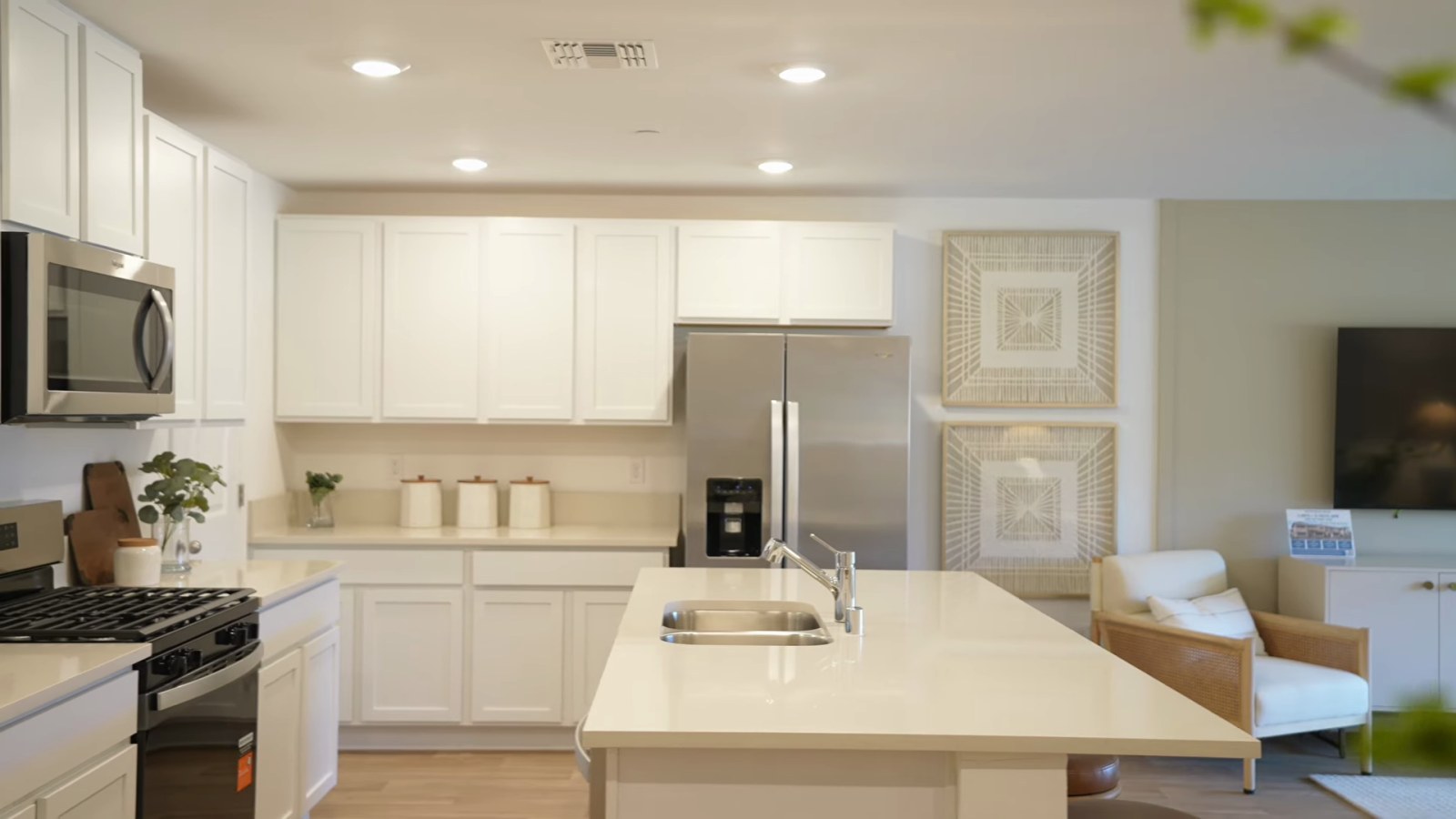 Pulte Branton model kitchen at Dalea at Aries with white cabinets, an island with seating, a stainless range and microwave