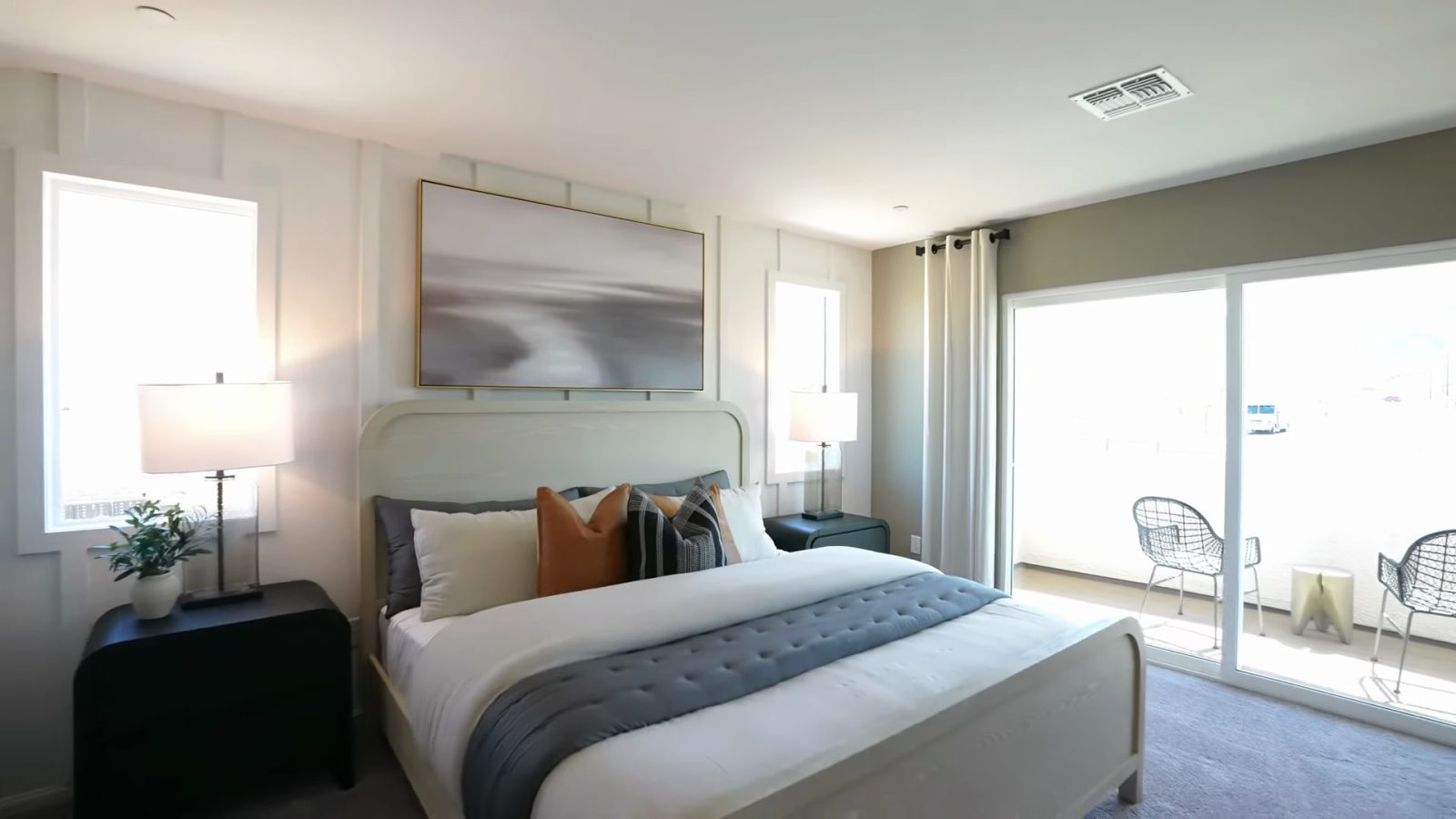 Primary bedroom in the Pulte Danbury model at Dalea at Aries with a king bed, two windows and a sliding door to a small balcony