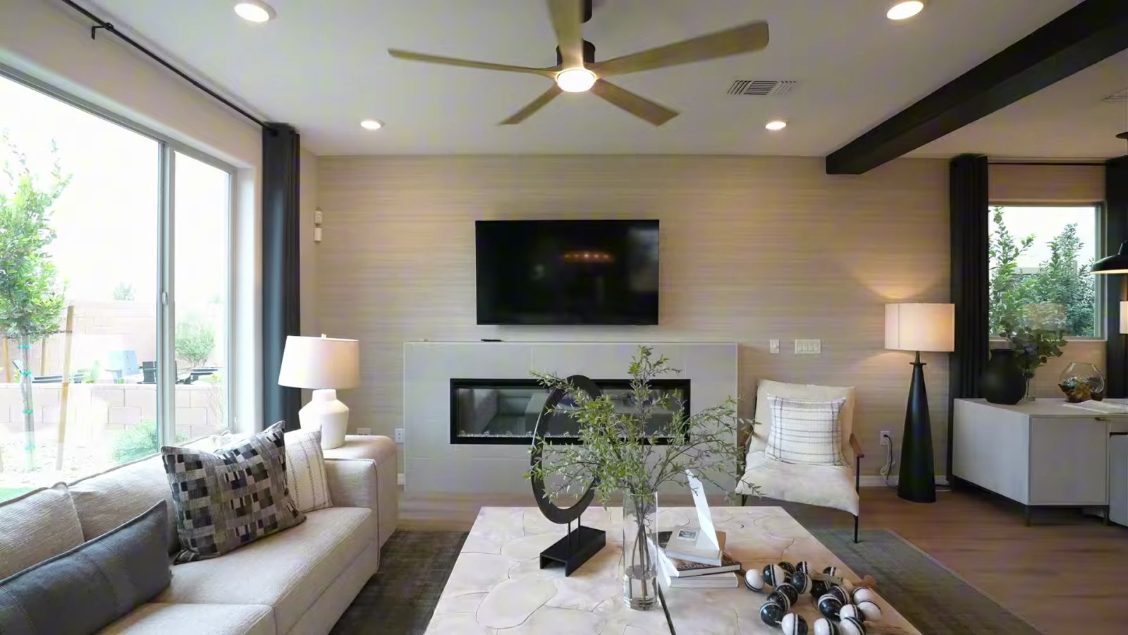 Gathering room in the Pulte Juniper model at Cordora with a linear fireplace, wall-mounted television, sectional sofa and ceiling fan