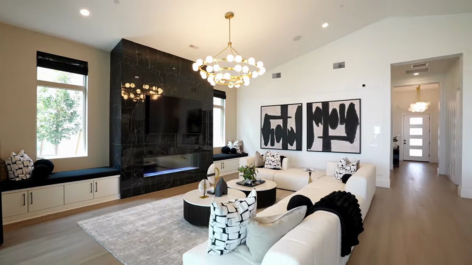 Great room in the Pulte Parklane single-story model at Brantley with the optional 15-foot ceiling, black stone fireplace wall, chandeliers and a cream sectional