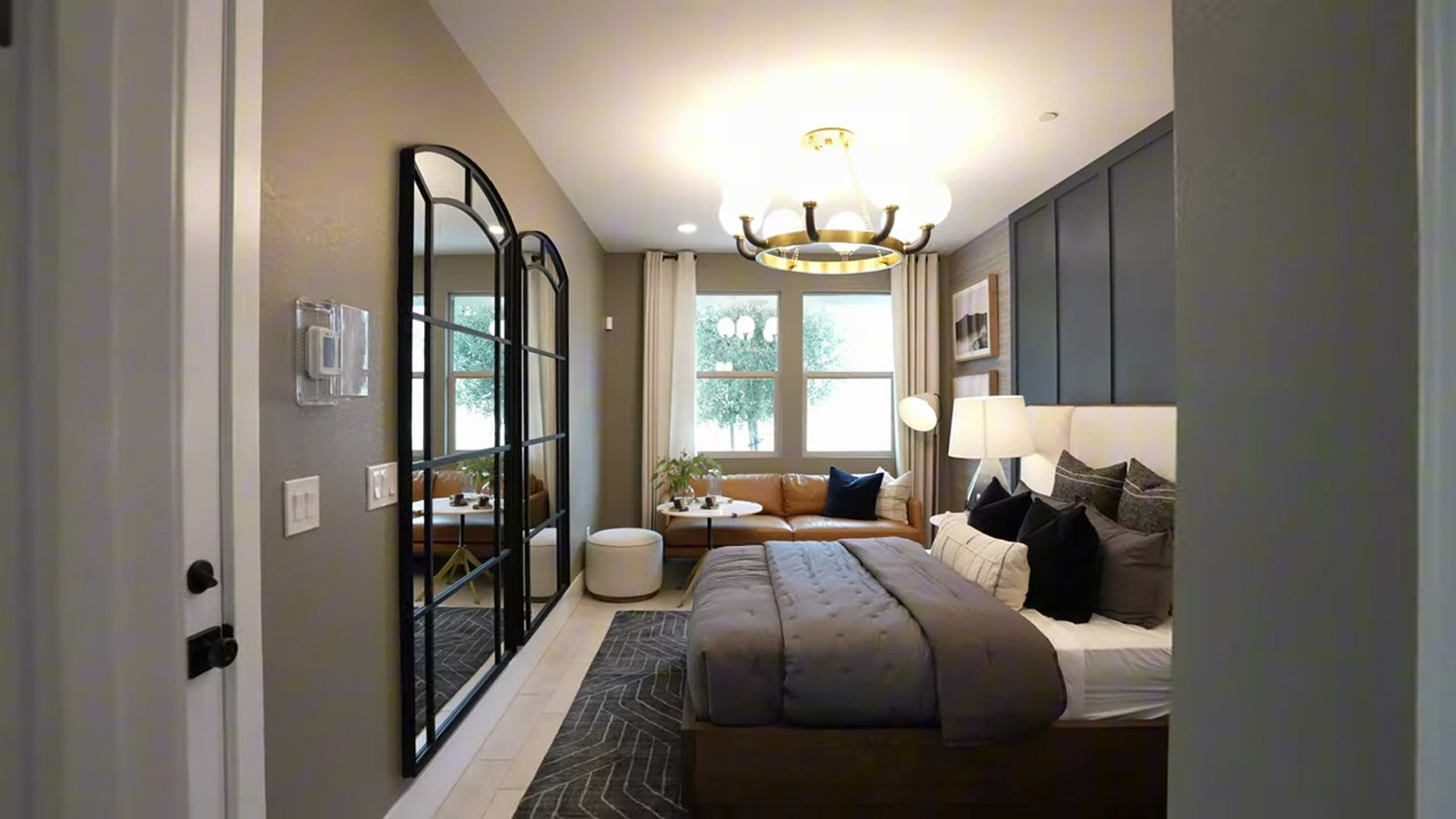 Private casita bedroom in the Pulte Tivoli model at Brantley in Summerlin, with a sitting area, arched glass door and upholstered bed