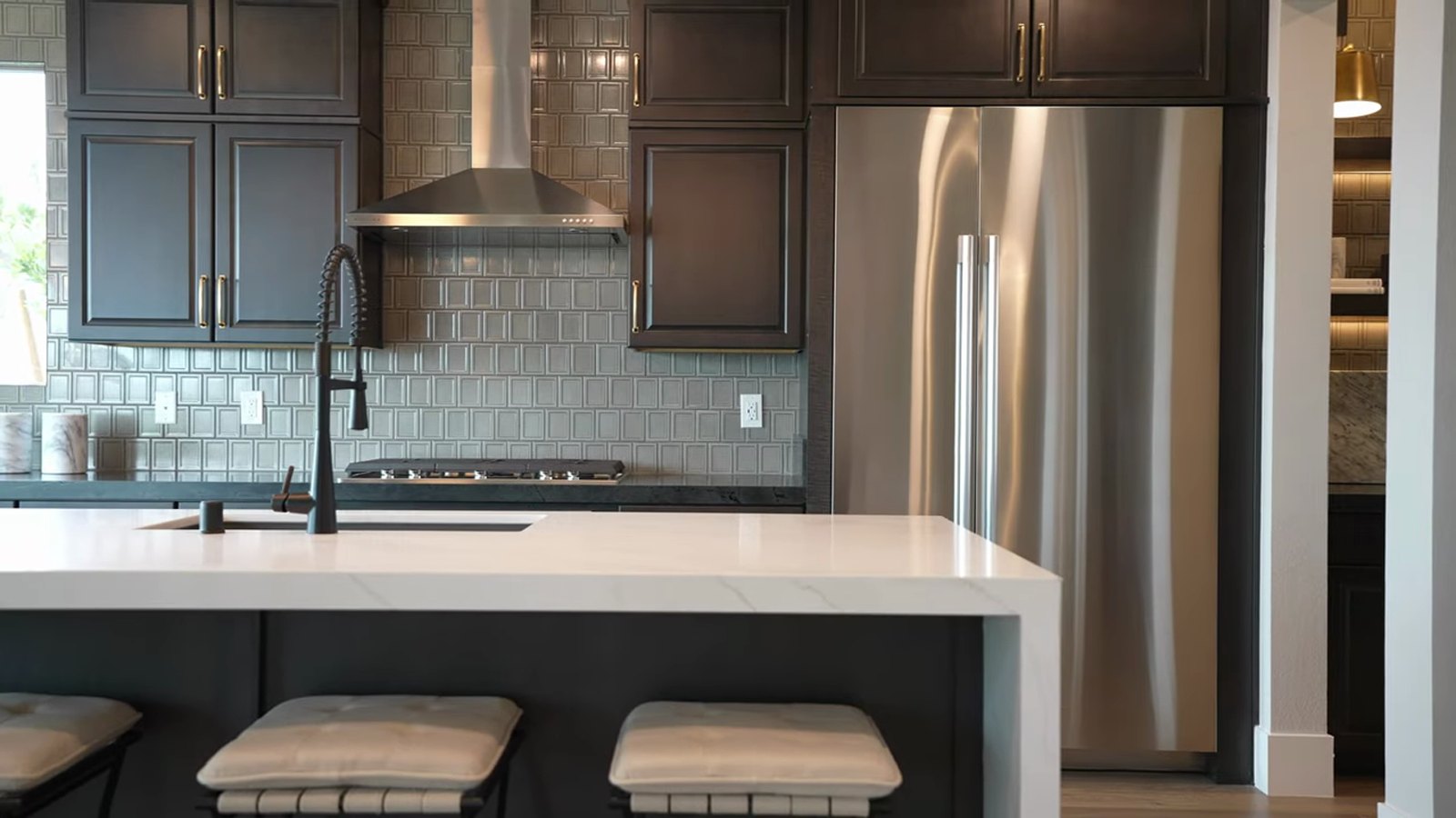 Kitchen in the Pulte Tivoli model at Brantley with dark cabinetry, a white quartz waterfall island and stainless appliances