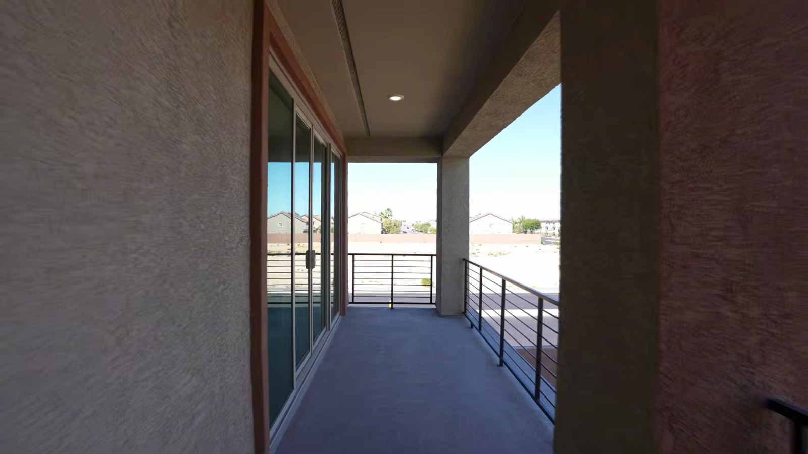 Covered main-level balcony off the gathering room in Pulte's White Pine model with a metal railing and sliding glass doors