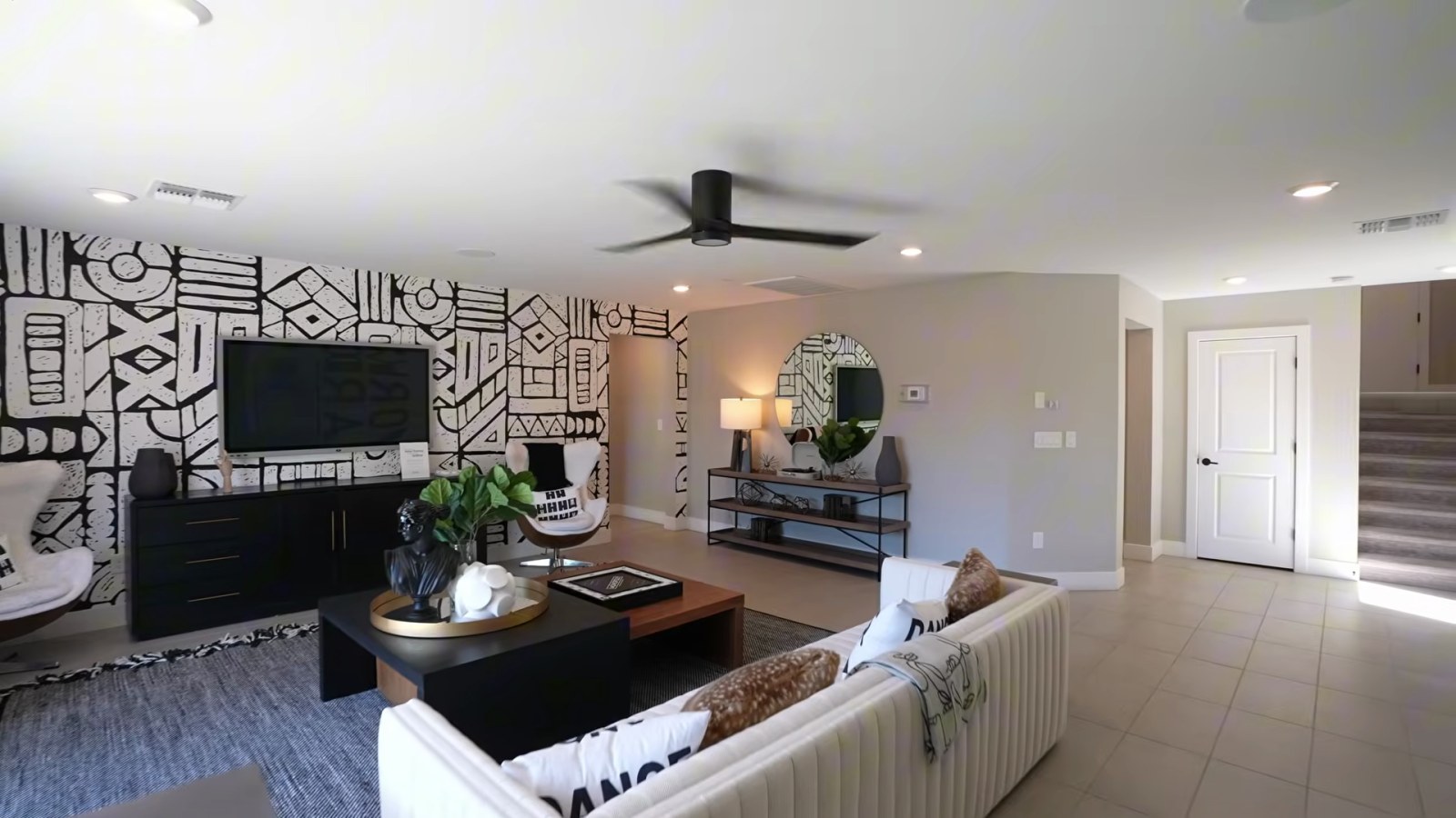 Lower-level game room in Pulte's White Pine model at Delamar with a sectional, media wall and the stair to the main floor