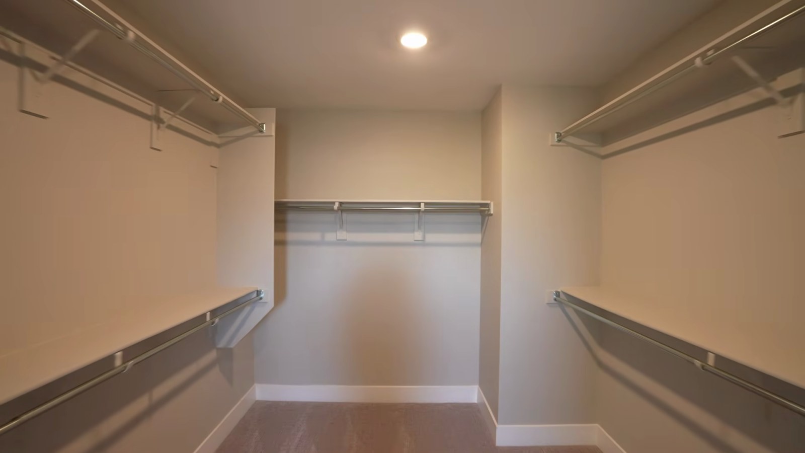 Long walk-in primary closet in Pulte's White Pine model with hanging rods and shelves on both sides
