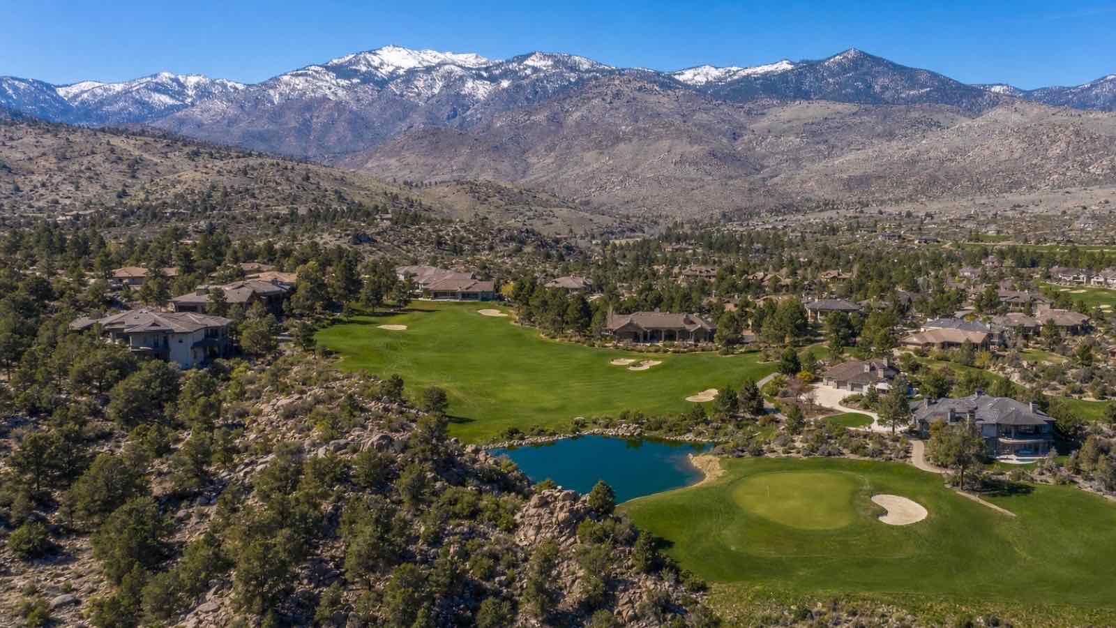 Aerial view of ArrowCreek golf holes and a pond below the Carson Range in the south Reno foothills