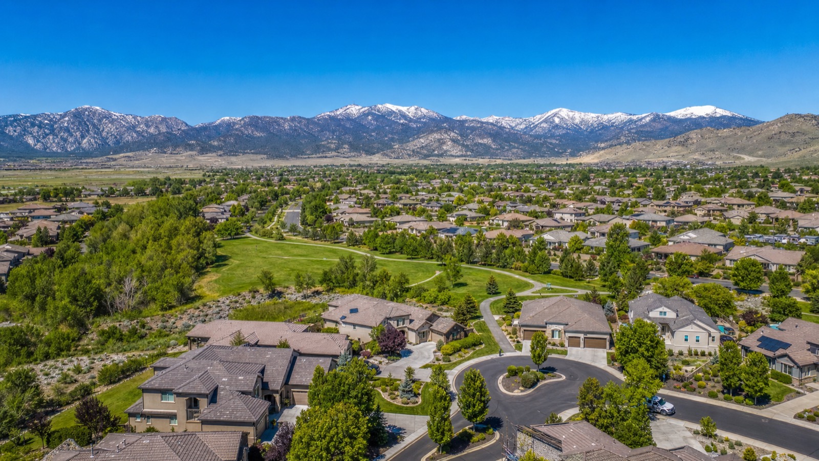 Aerial view of South Meadows homes and a greenbelt in South Reno with the Sierra Nevada and Mount Rose in the background