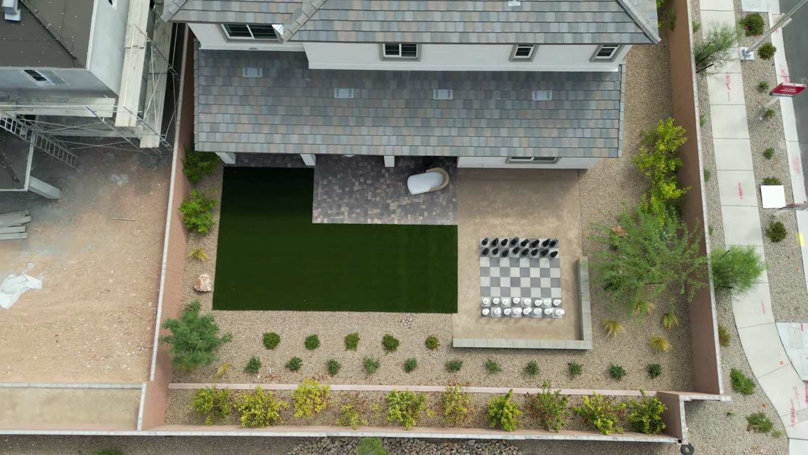 Aerial view of the Dayton model backyard at Silver Bow with artificial turf and pavers beside a neighboring dirt lot