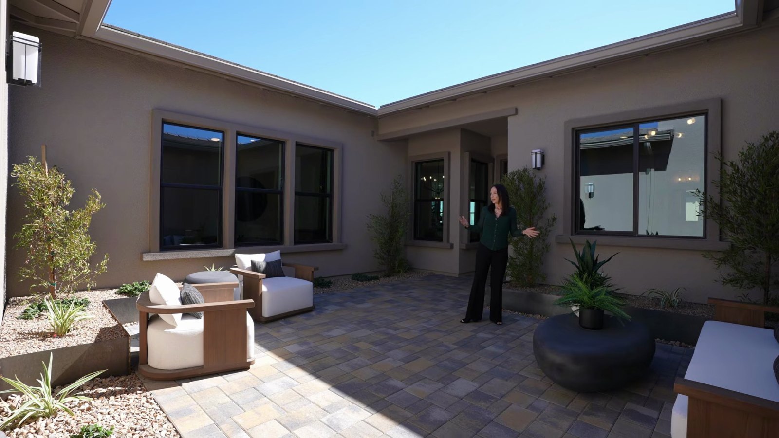 Front courtyard of the Richmond American Rowan model at Cactus Bloom with pavers, lounge chairs and desert planting enclosed by the house