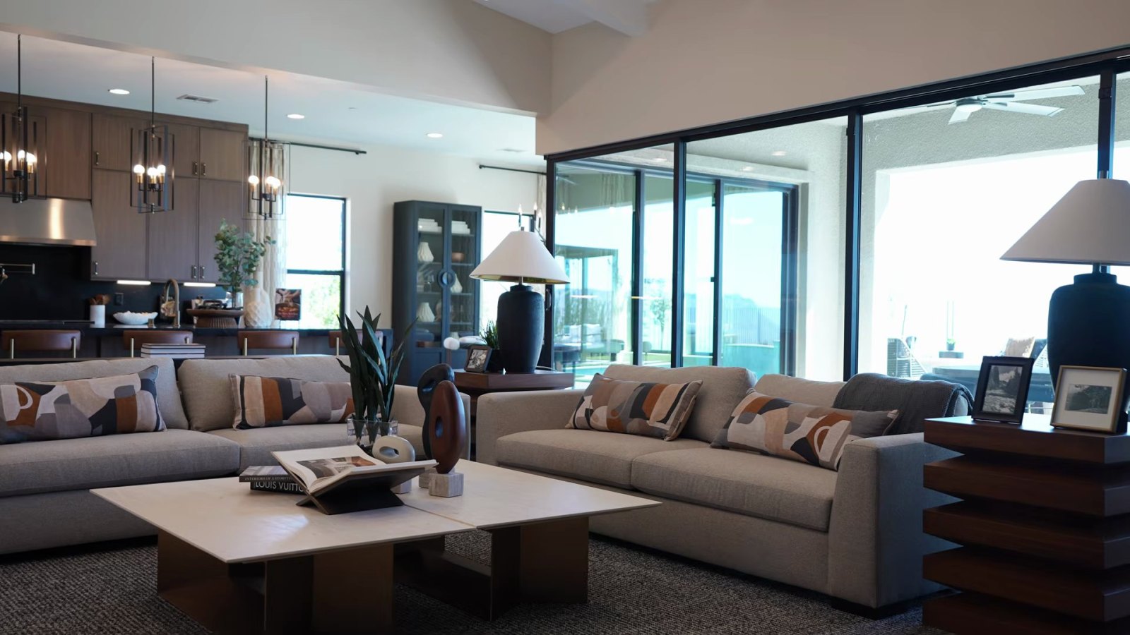 Great room in the Richmond American Rowan model with two sofas, the kitchen behind and floor-to-ceiling multi-slide glass doors to the patio