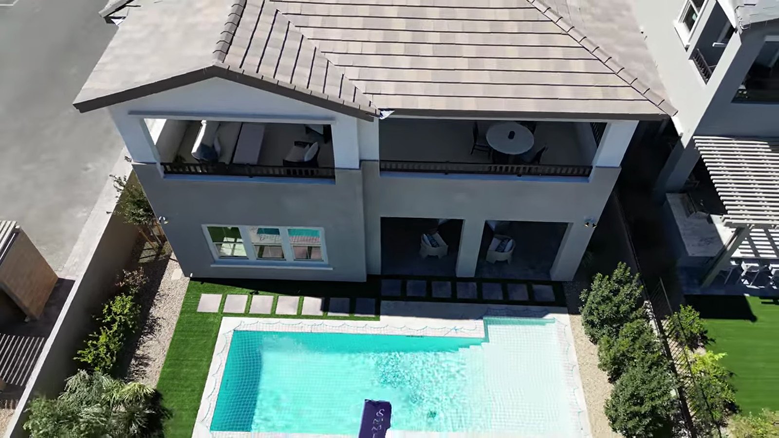 Aerial view of the Teton model backyard at Primrose Park with a pool, artificial turf, covered patio and upstairs balcony