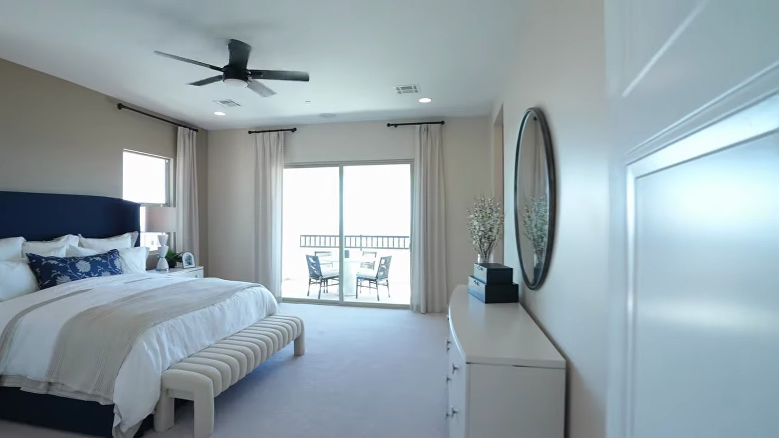 Primary bedroom in the Richmond American Teton model with a king bed and sliding doors to a covered balcony