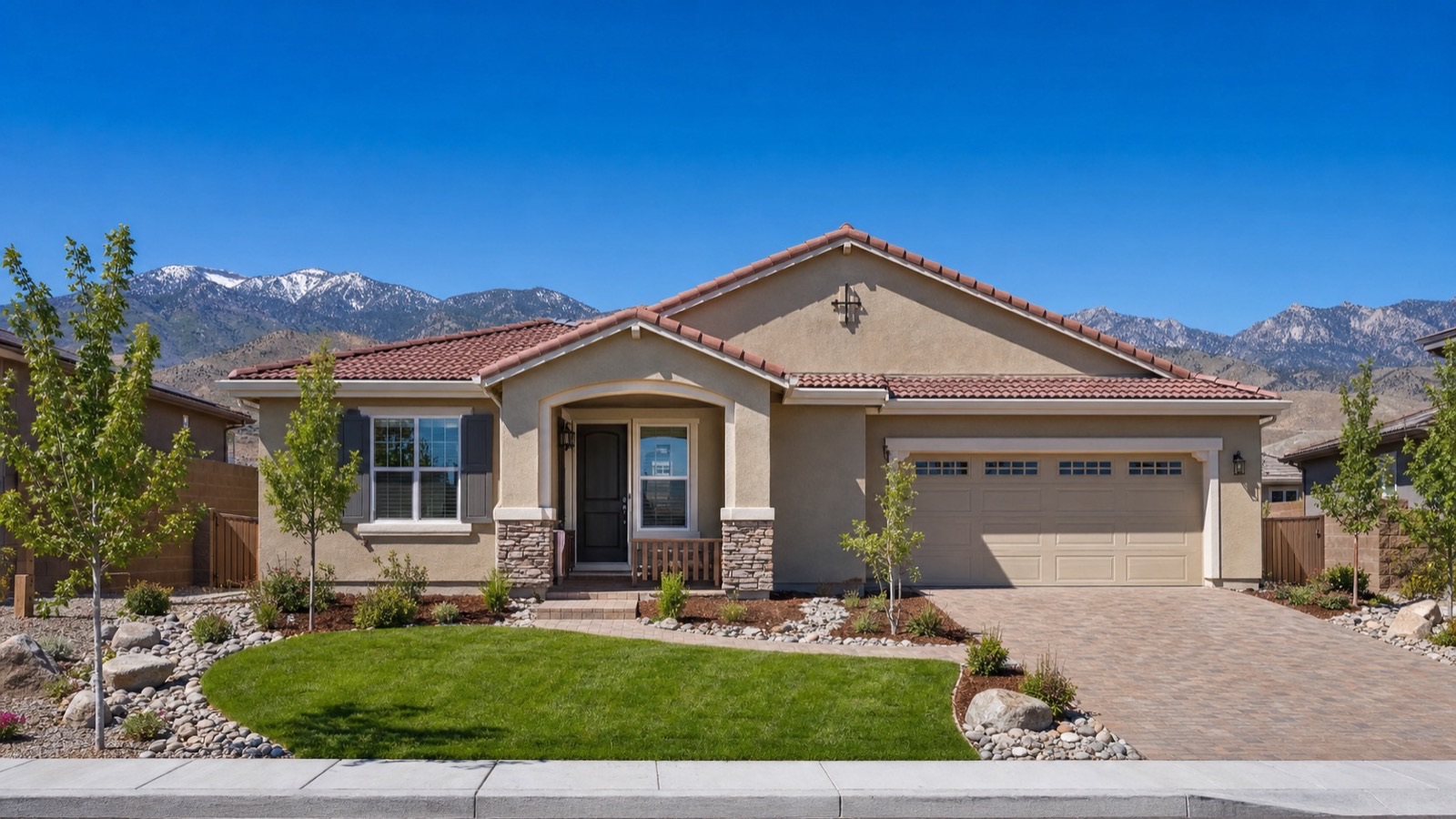Single-story Reno home with a tile roof, paver driveway and lawn below the snow-capped Carson Range