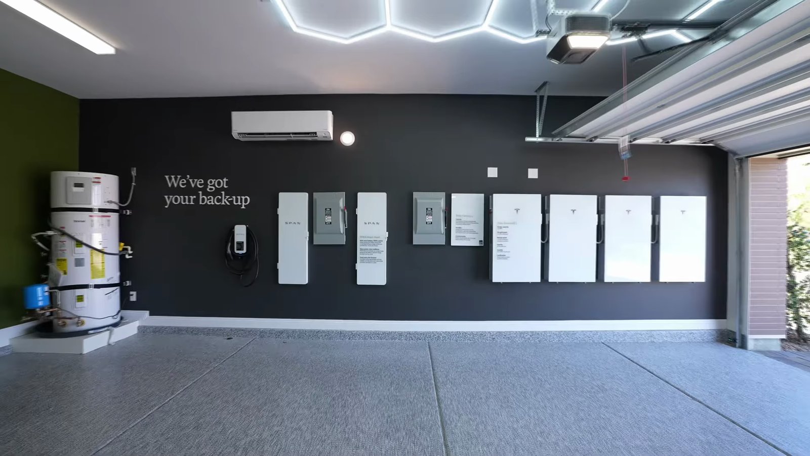 Garage equipment wall in the Shawood Kagari model with smart electrical panels, four home batteries, an EV charger and a water heater