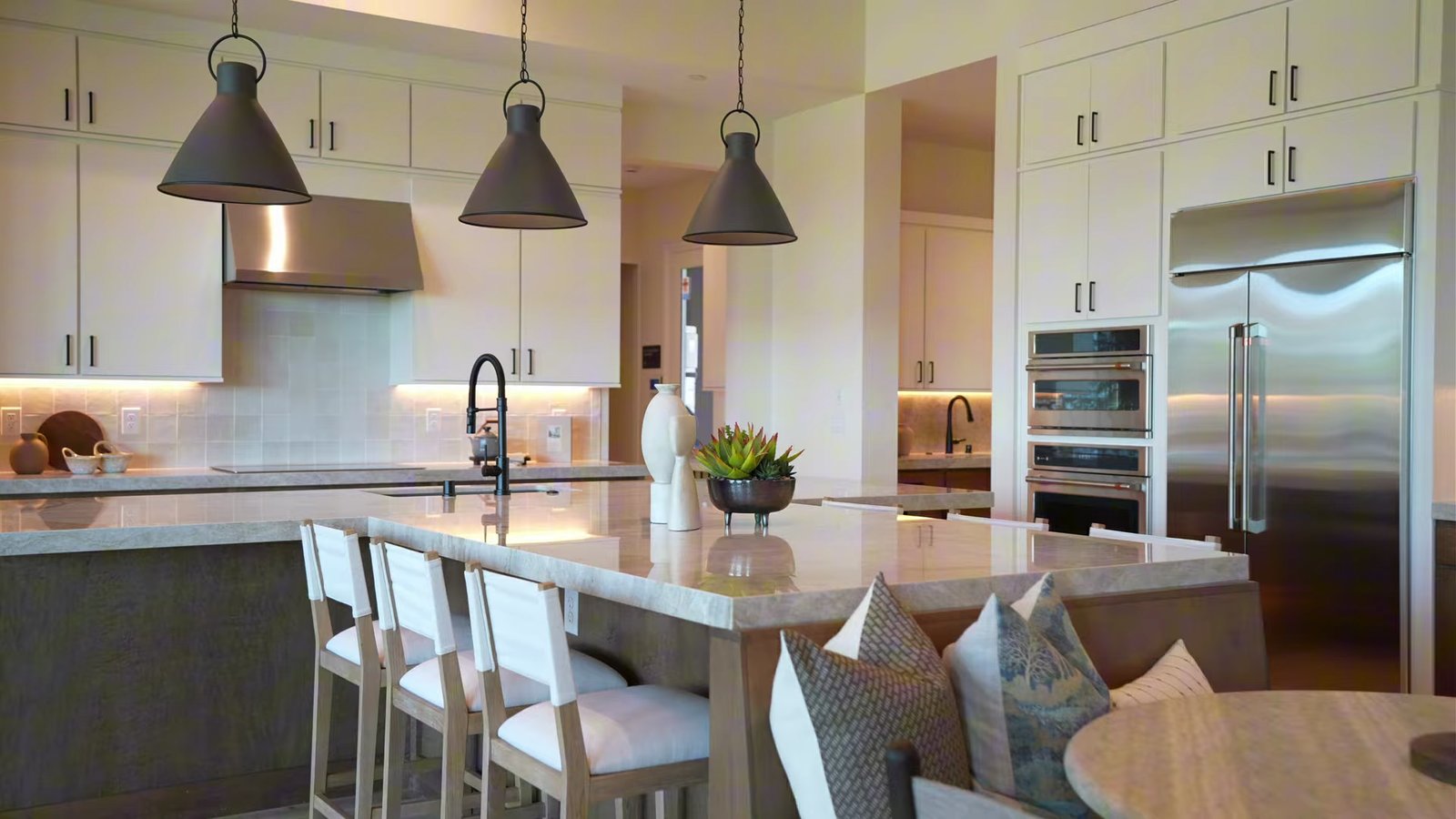 Shawood Kagari model kitchen with a T-shaped quartz island, counter stools, pendant lights and two-tone cabinetry