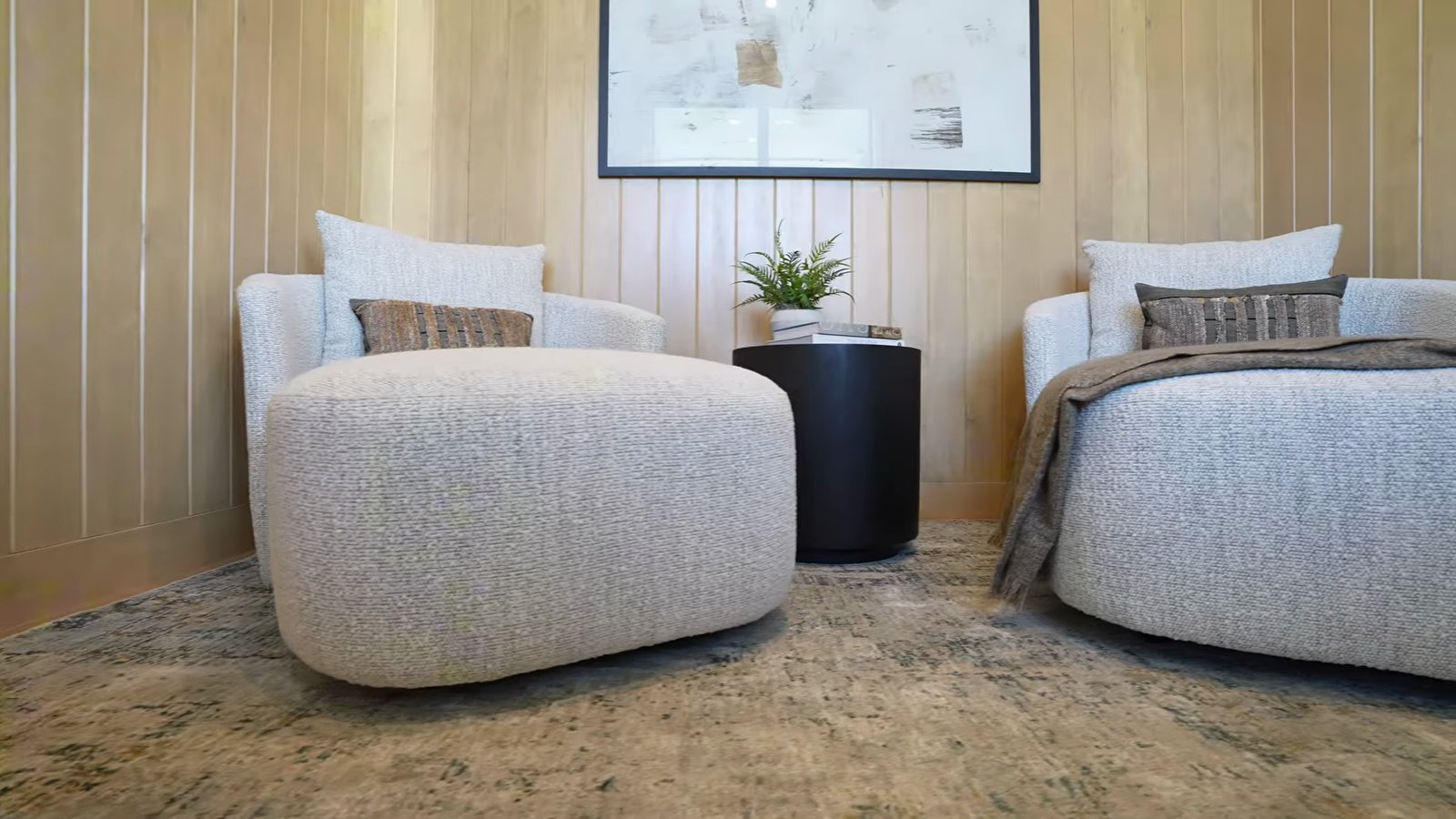 Primary retreat room in the Shawood Kagari model with wood-paneled walls, two upholstered lounge chairs, a round side table and a potted fern