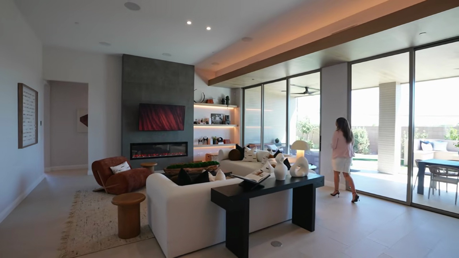 Shawood Towa great room with a stone fireplace wall, built-in shelving and sliding glass walls to the covered patio
