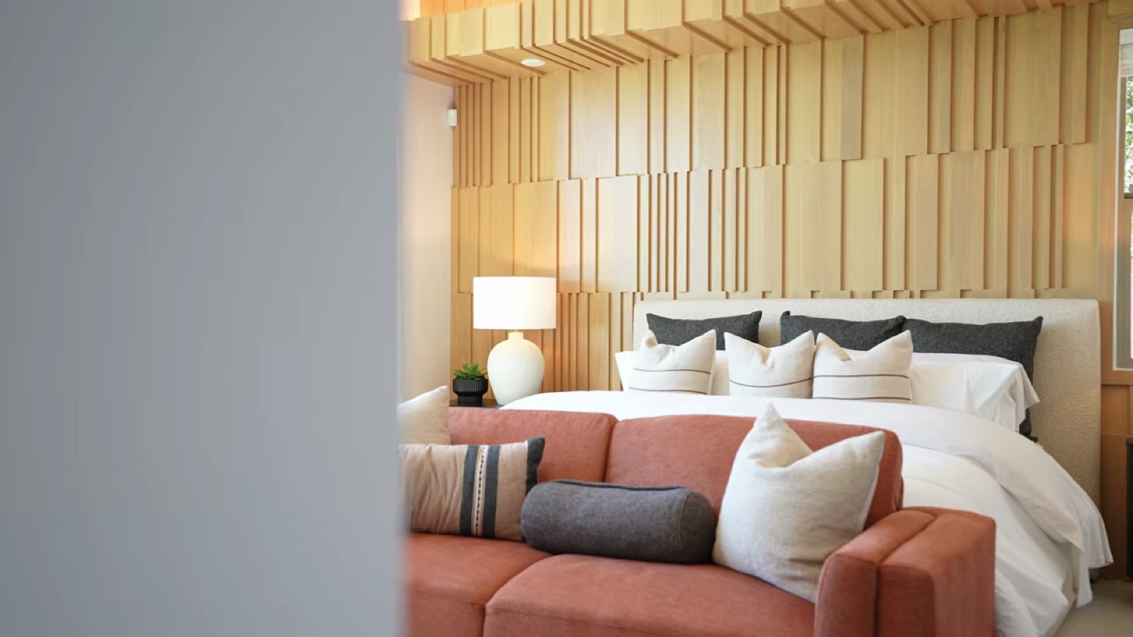 Shawood Towa primary bedroom with a wood slat accent wall, king bed and a sofa at the foot of the bed