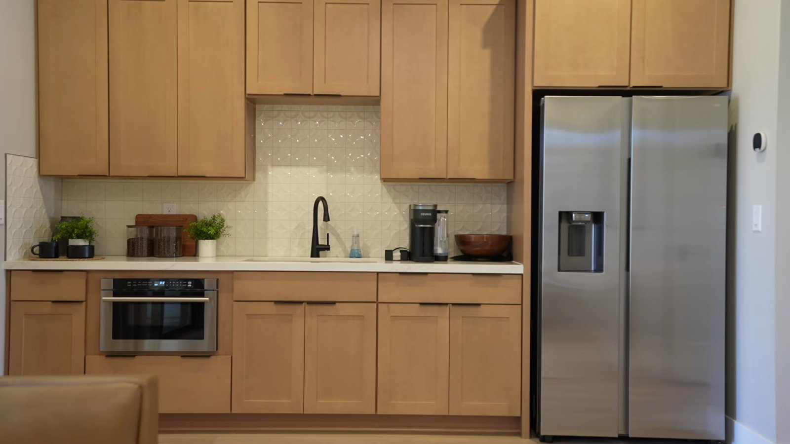 Kitchenette in the Quartet model's suite with light wood cabinets, a microwave drawer, a sink and a stainless refrigerator