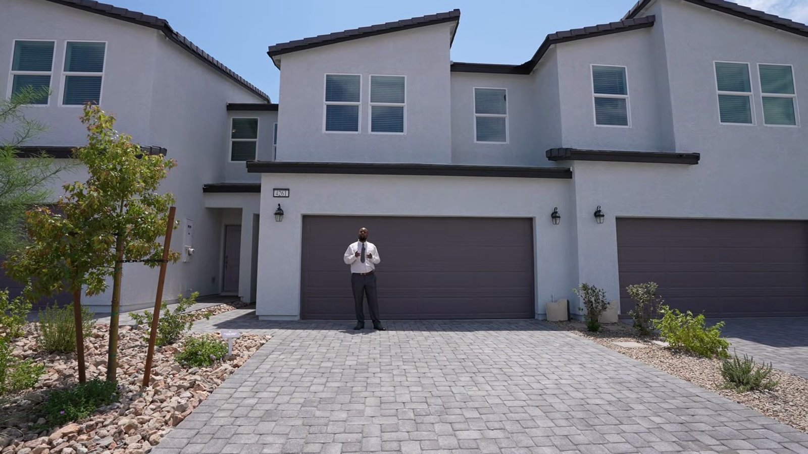 Two-story StoryBook townhome building at Parkhill Crest with a dark two-car garage door, gray paver driveway and young desert landscaping