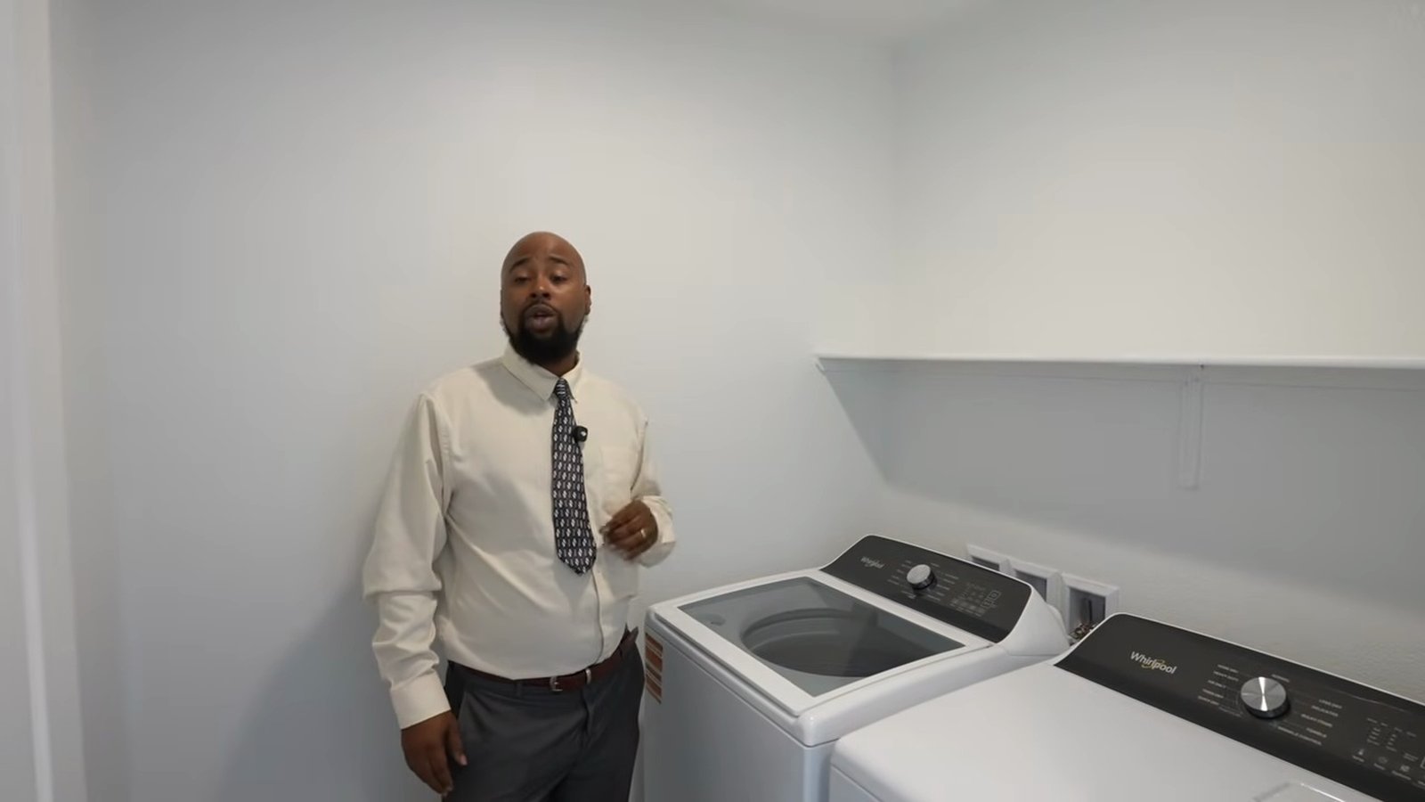 Upstairs laundry room in the Arroway model with a white top-load washer and matching dryer under a shelf