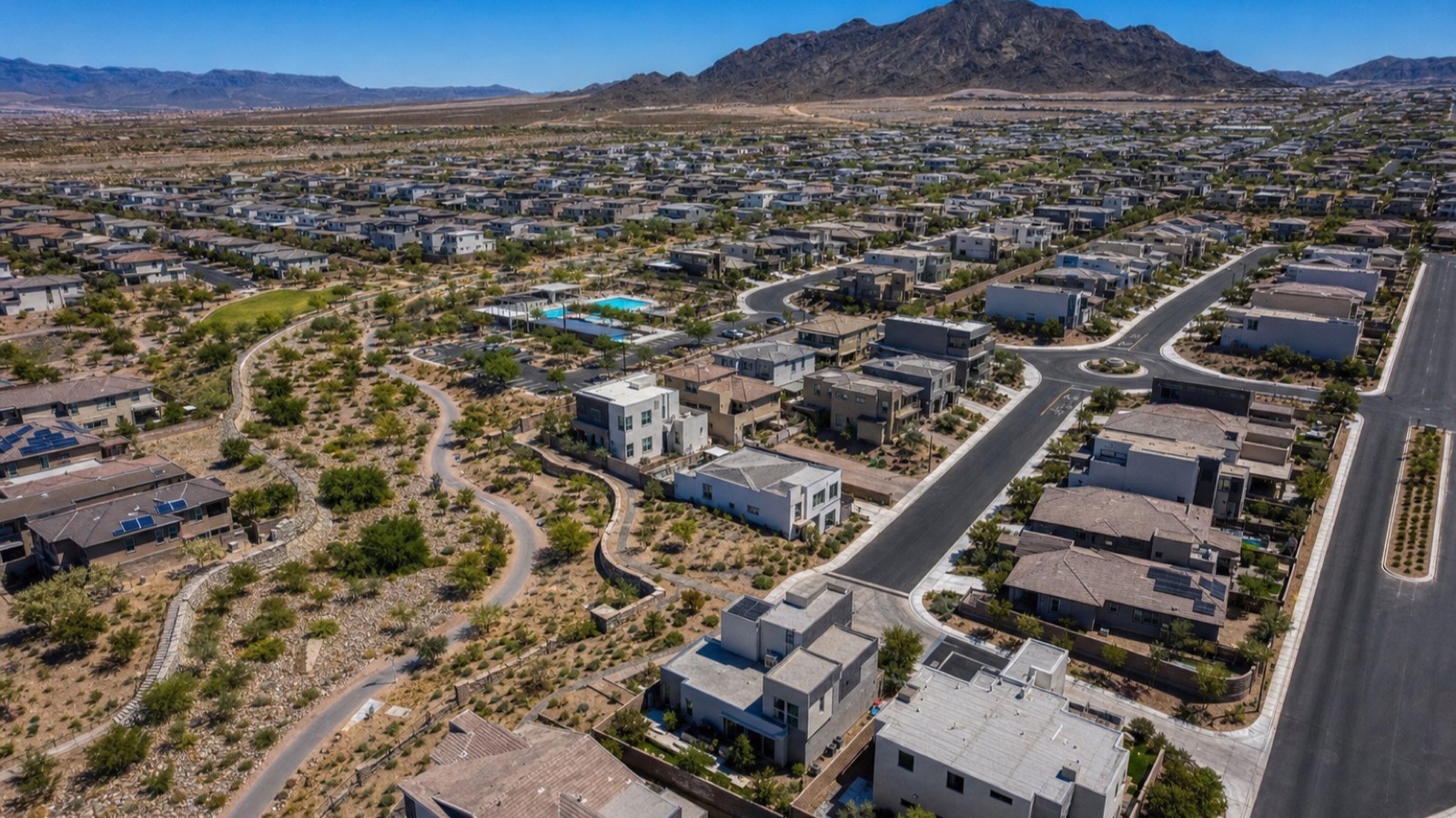 Aerial of Inspirada in south Henderson showing a resident pool, desert trail corridors and contemporary two-story homes below the desert mountains