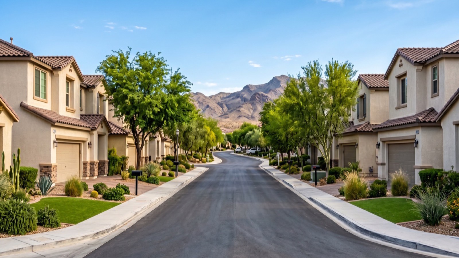 Tree-lined Henderson residential street of two-story stucco homes with tile roofs rising toward the desert foothills