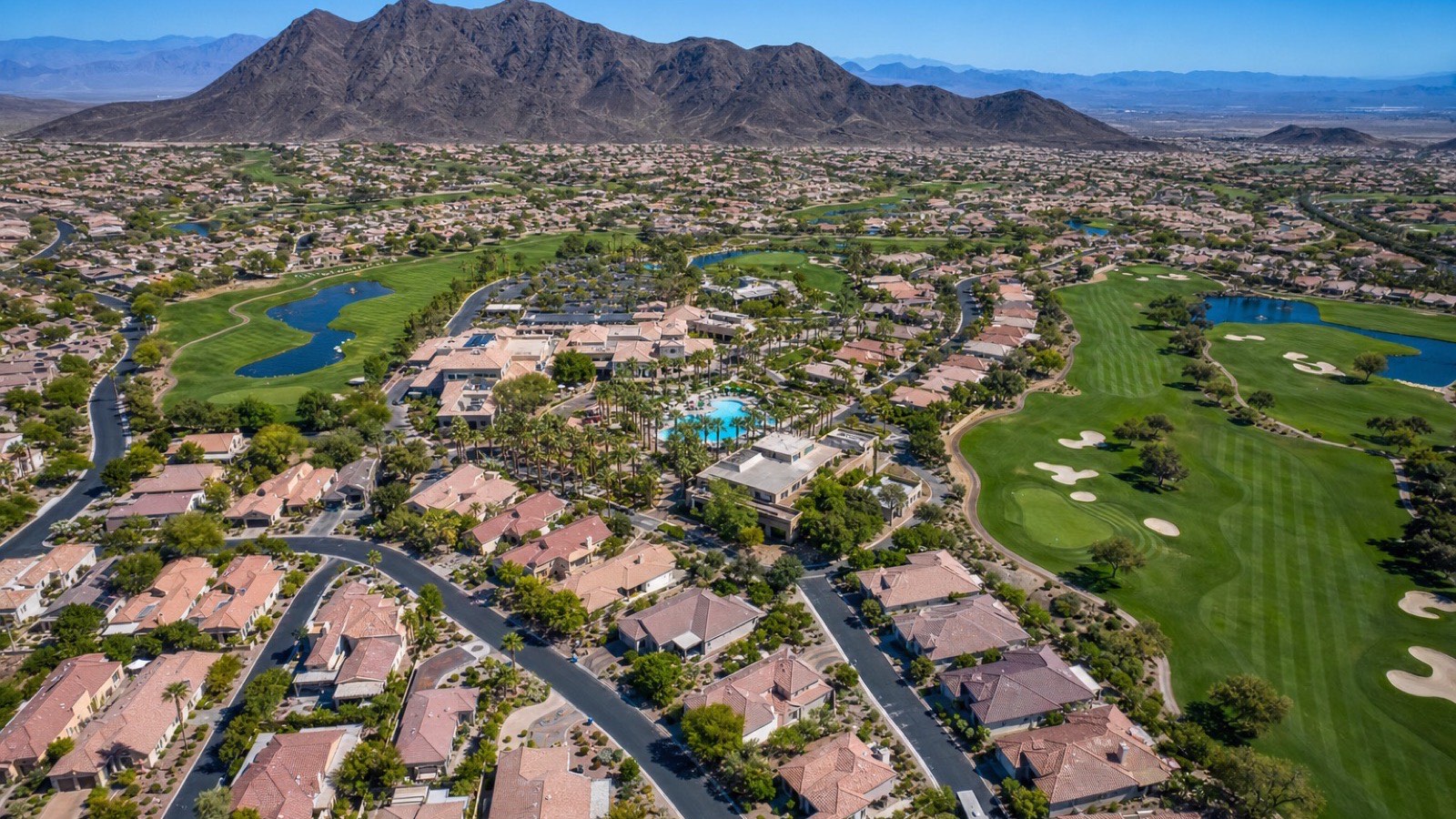 Aerial view of Sun City Anthem's single-story homes and golf courses on the Henderson foothills with the Las Vegas valley beyond