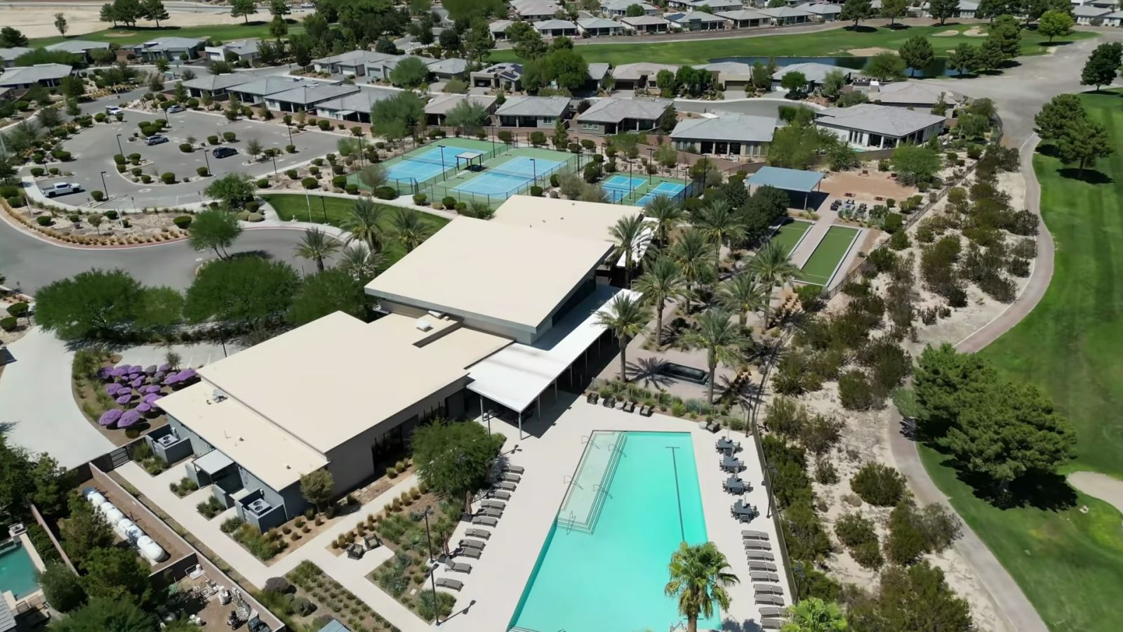 Aerial view of the Ovation clubhouse at Mountain Falls in Pahrump with a lap pool, tennis and pickleball courts and single-story homes around it