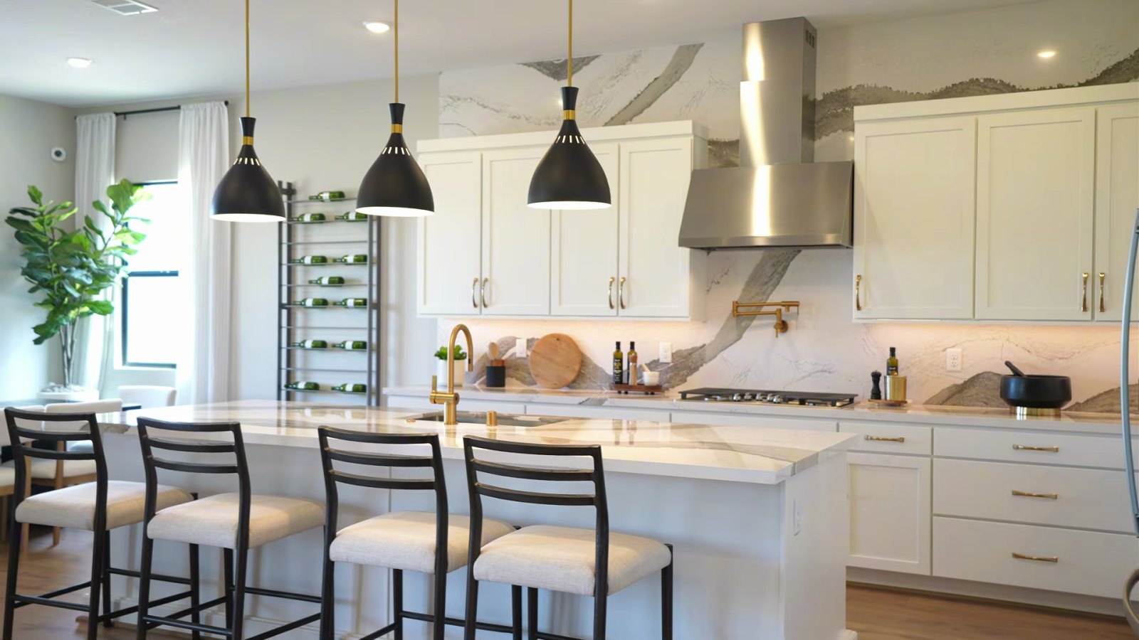 Heritage model kitchen at Ashland with a white quartz island, black pendant lights, white shaker cabinets to the ceiling, a full-height quartz backsplash and a stainless hood