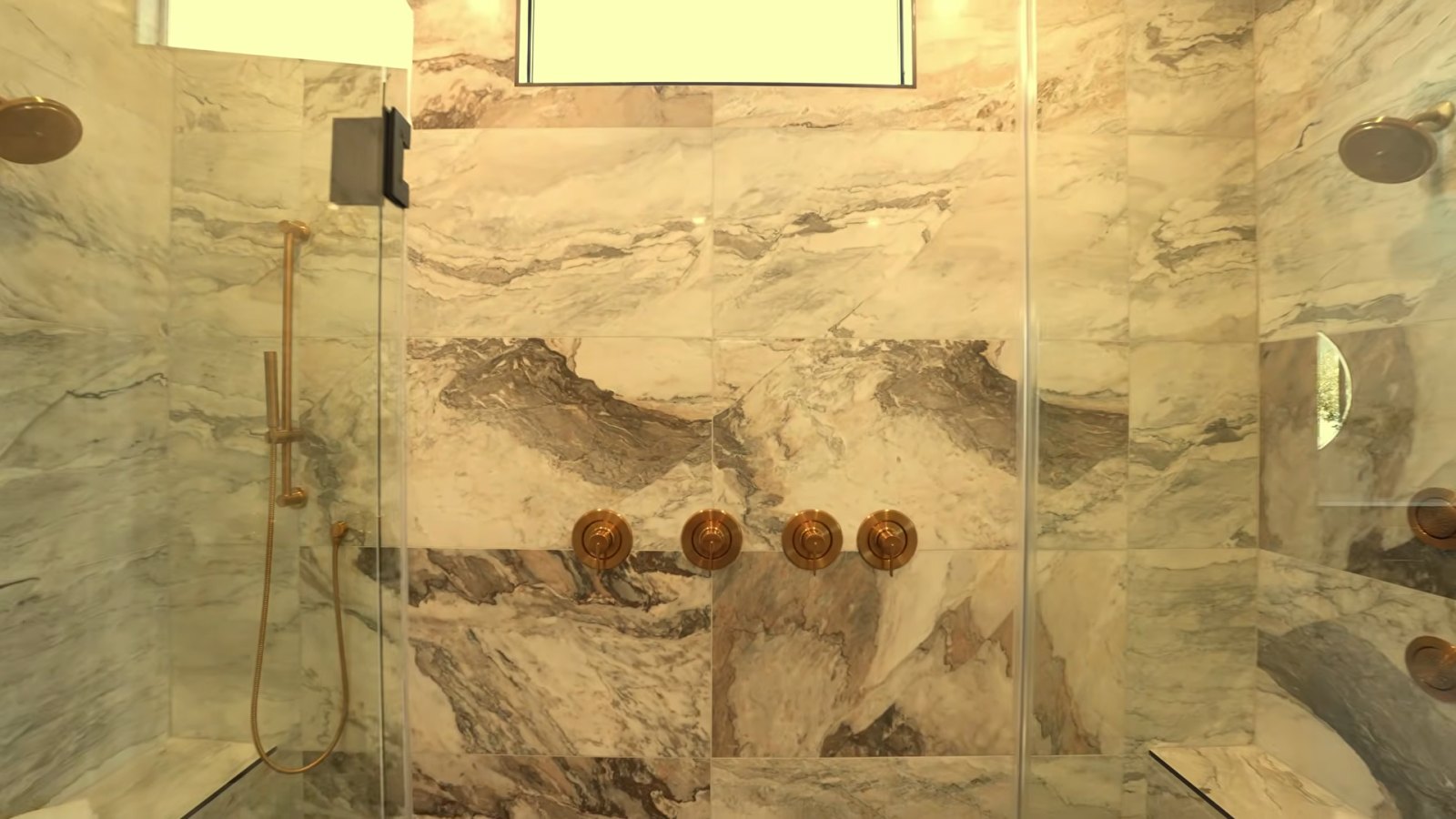 Upgraded walk-in super shower in the Heritage model primary bath with marble-look tile from floor to ceiling, brass fixtures and controls on both sides