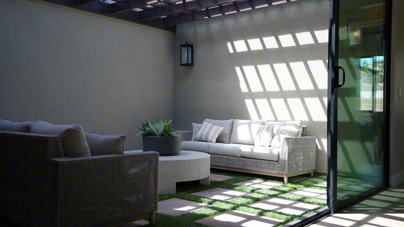 Interior courtyard in the Taylor Morrison Summit model at Ashland with corner-meet sliding glass doors, a trellis, turf pavers and outdoor seating