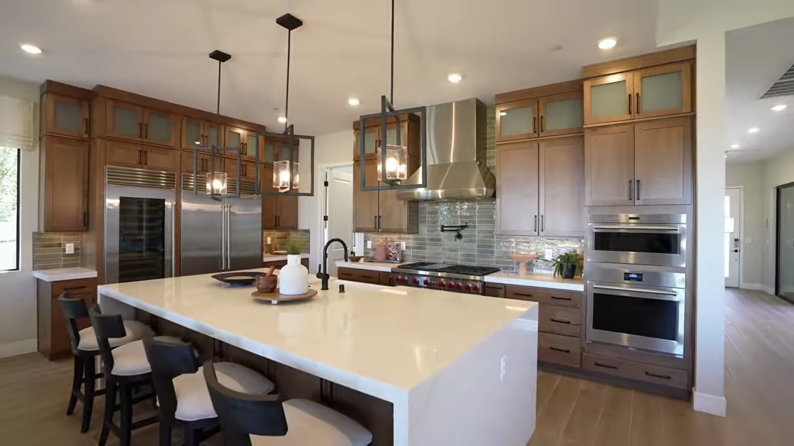 Summit model kitchen at Ashland with a waterfall quartz island, Sub-Zero refrigerator column, Wolf double ovens and a stainless range hood